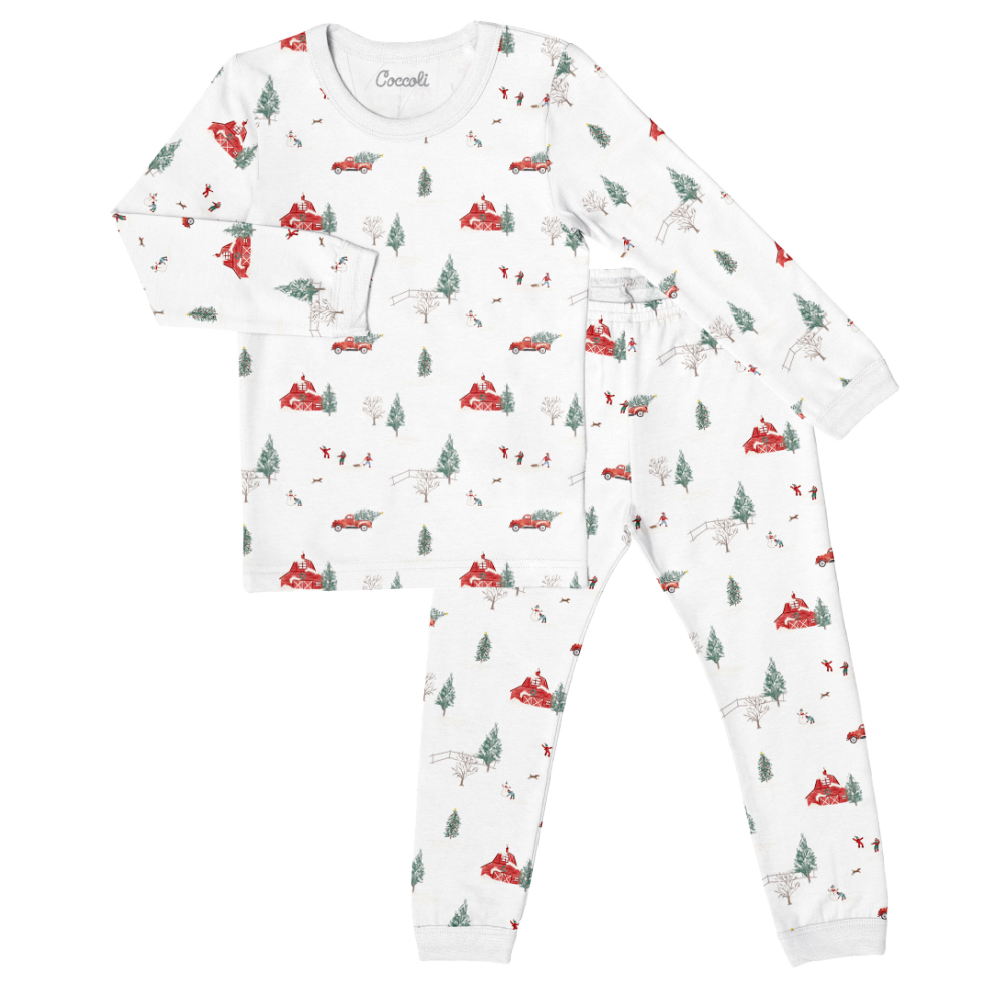 A set of white baby pajamas with a winter scene print, including trees and snow.